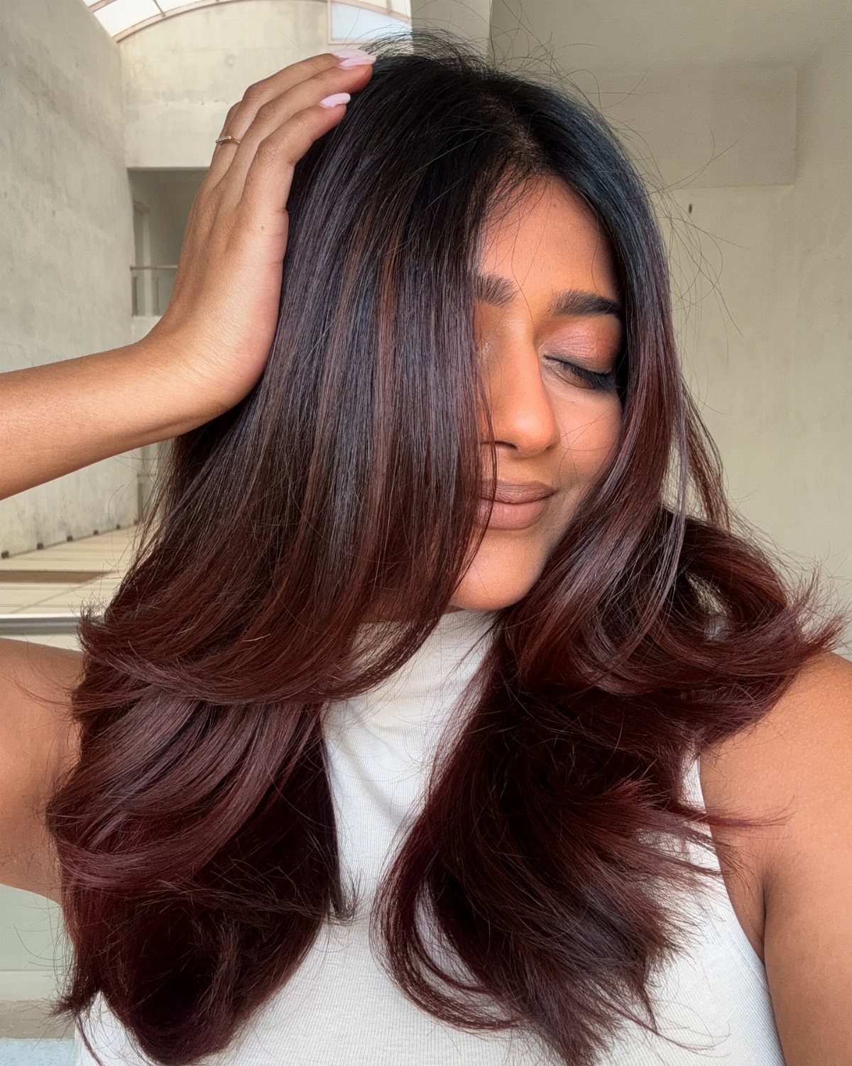 Woman's layered espresso hair blends into warm bronze and auburn ends