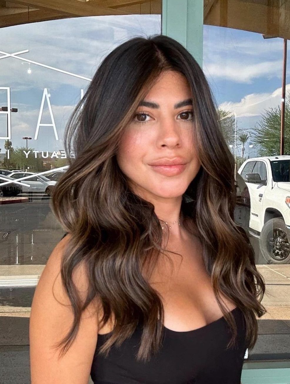 Woman with long brunette waves showing subtle caramel and chestnut balayage highlights