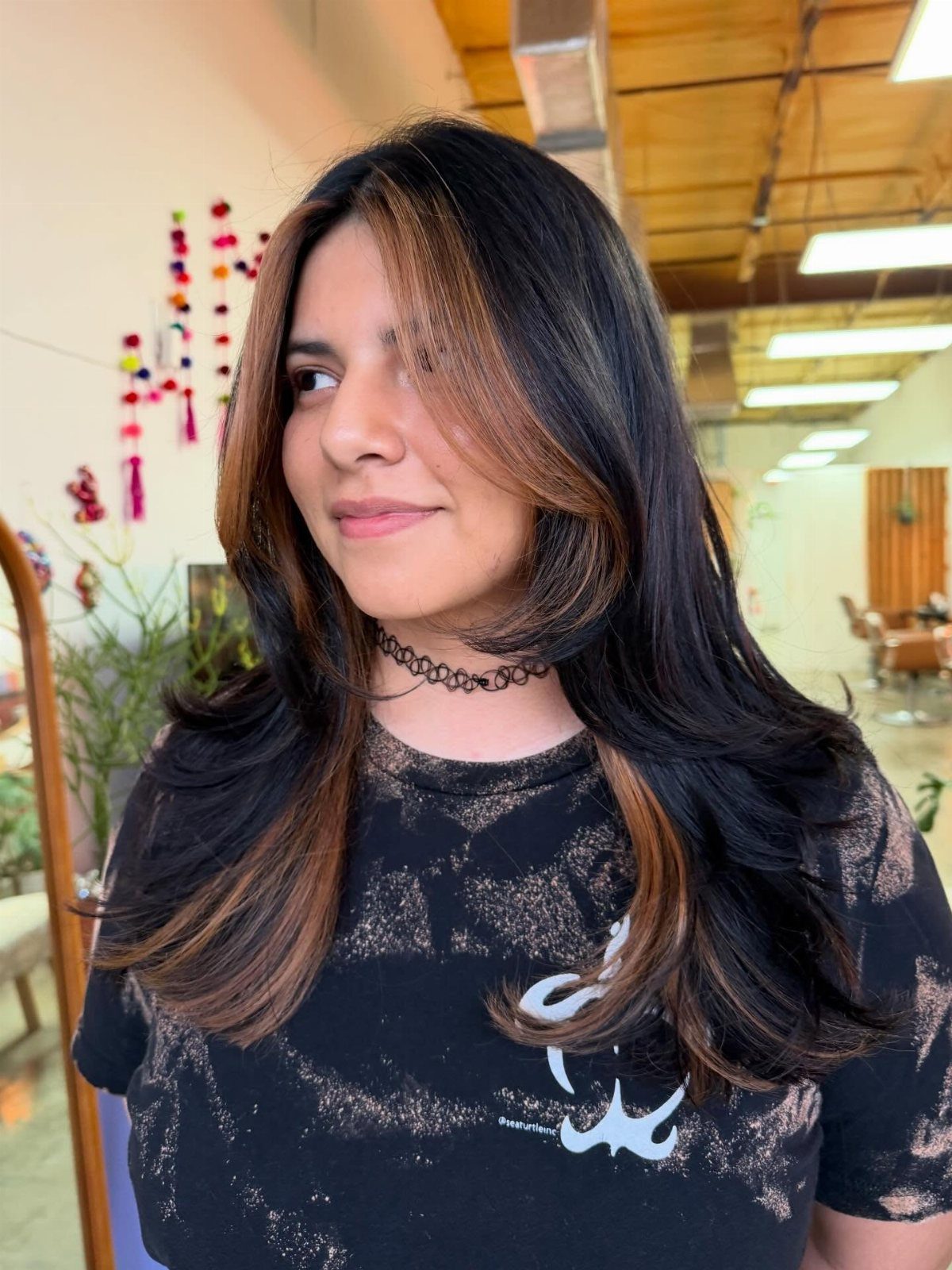 Woman with long black hair and cool brown face-framing highlights