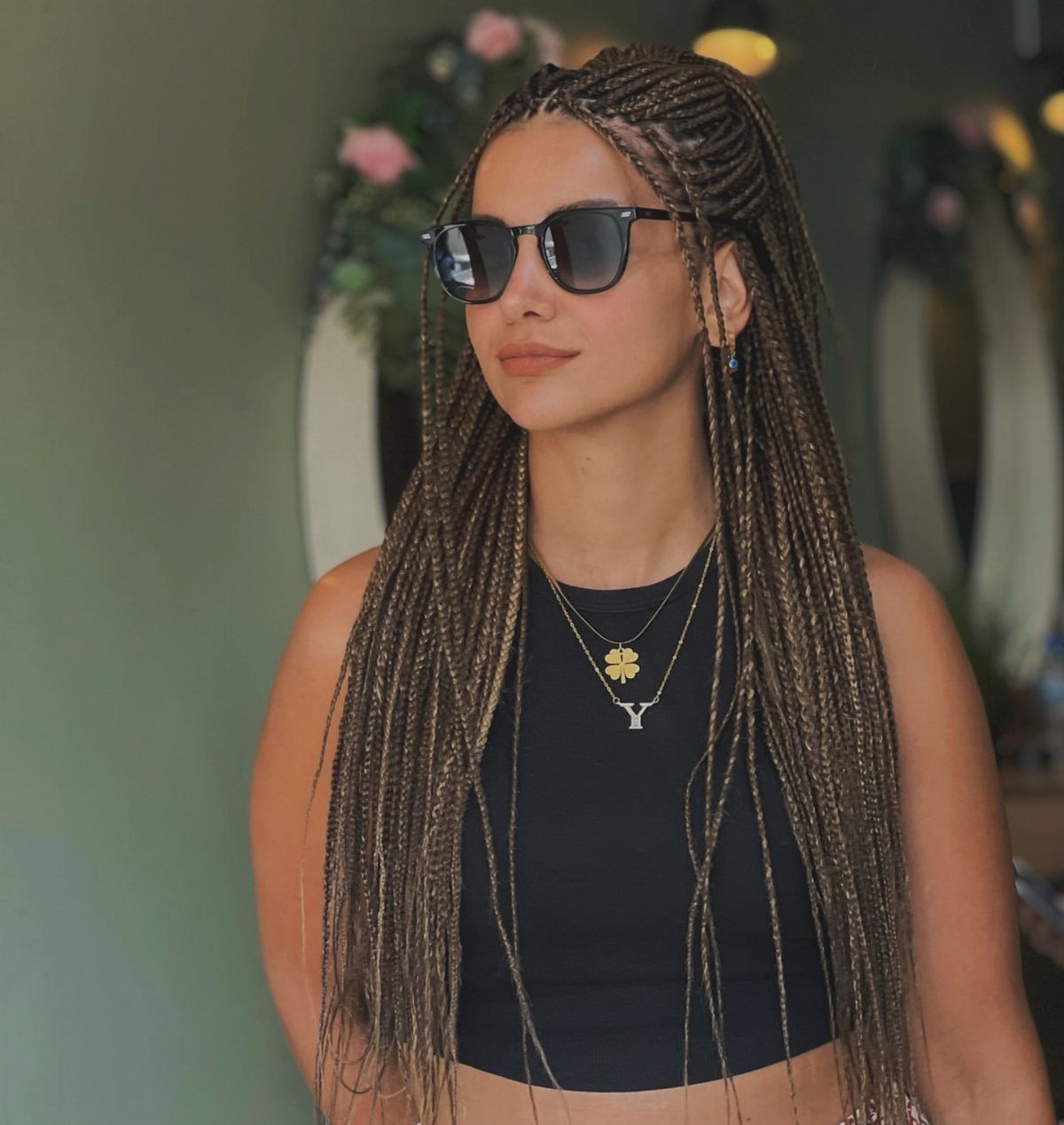 Woman with long dark and light brown box braids wearing sunglasses and a black top