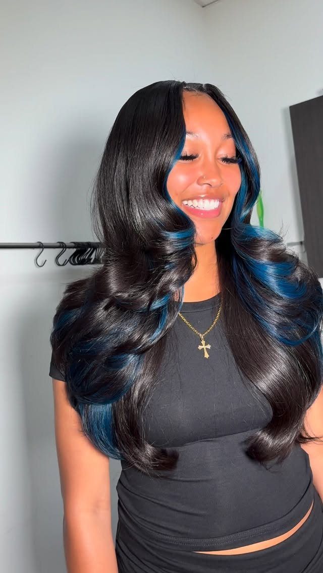 Woman with long black curls featuring vivid blue streaks around the face and through the lengths