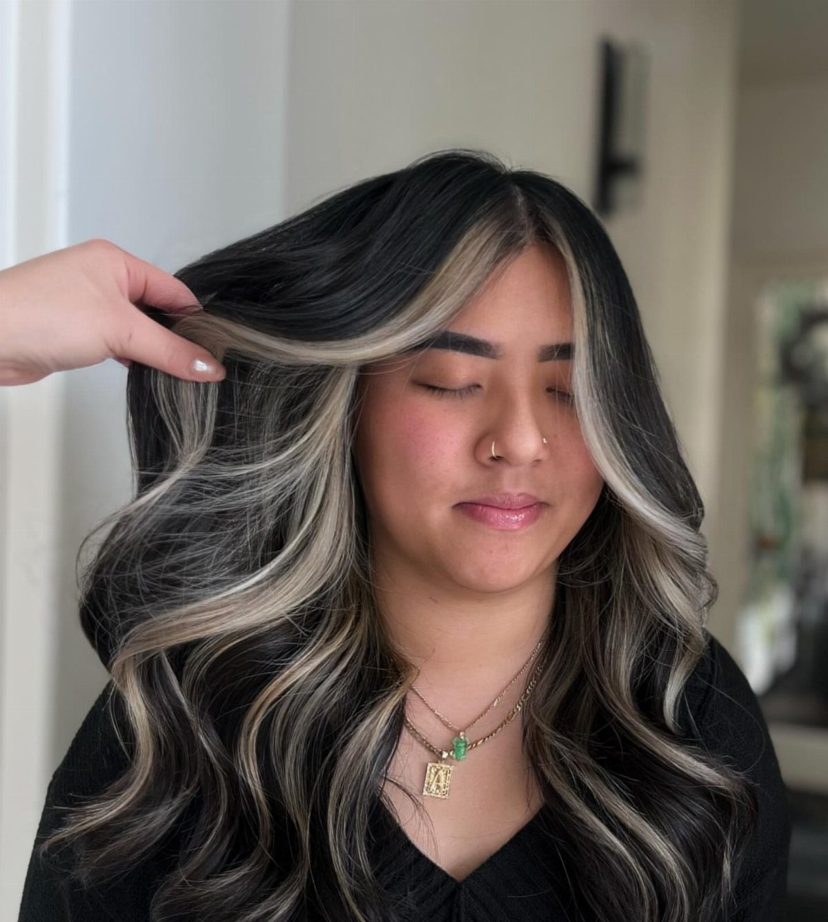 Long black waves with creamy blonde balayage and dark, softly blended roots