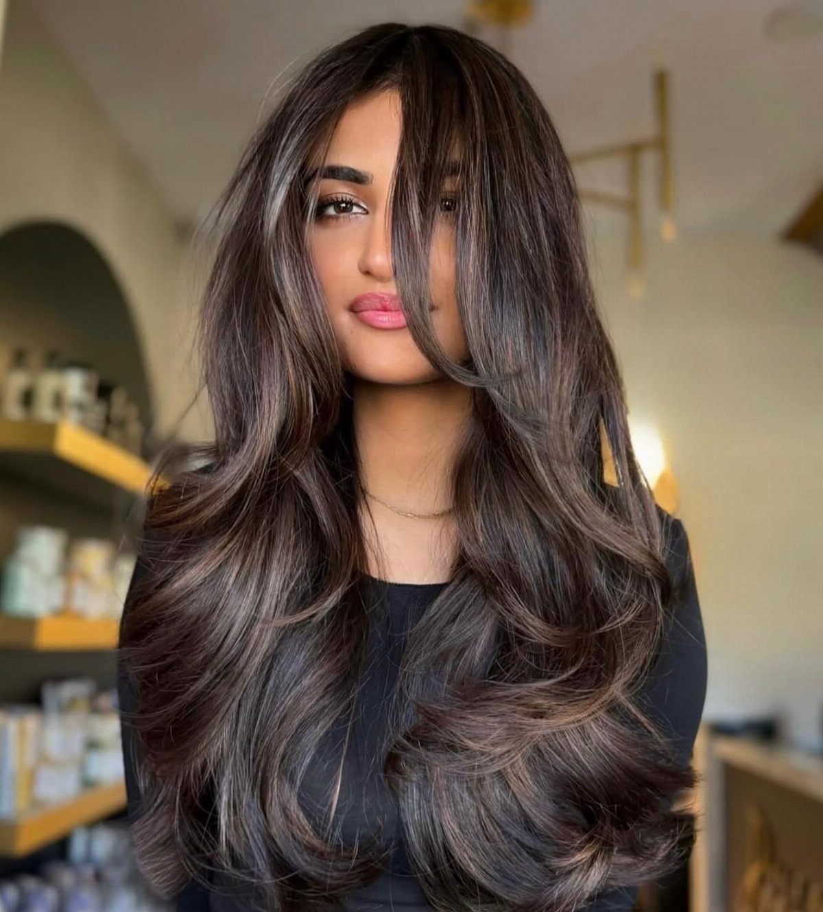 Woman with long, voluminous dark hair and subtle chocolate-brown highlights