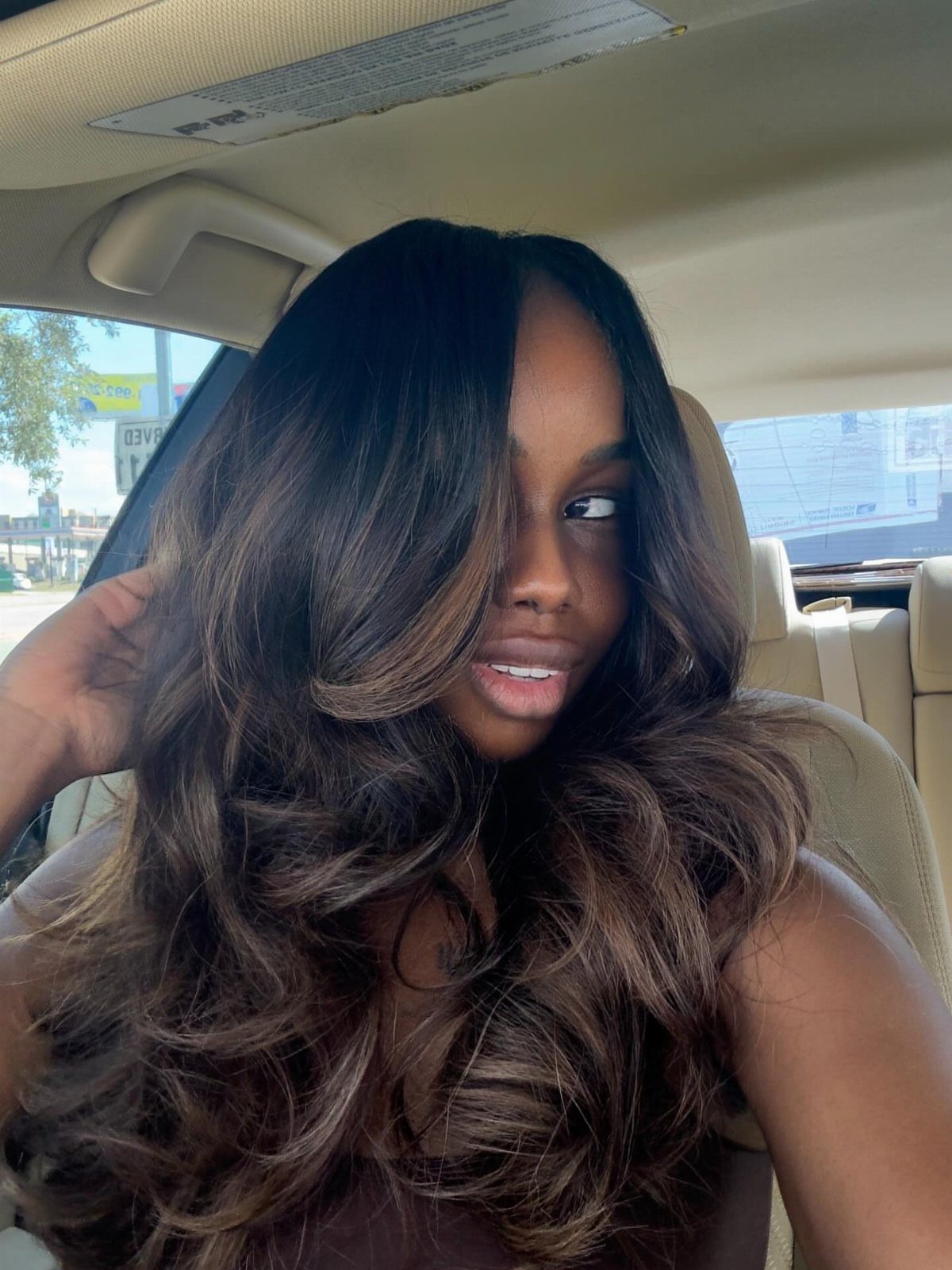 Woman shows long black curls with deep reddish-brown highlighted ribbons