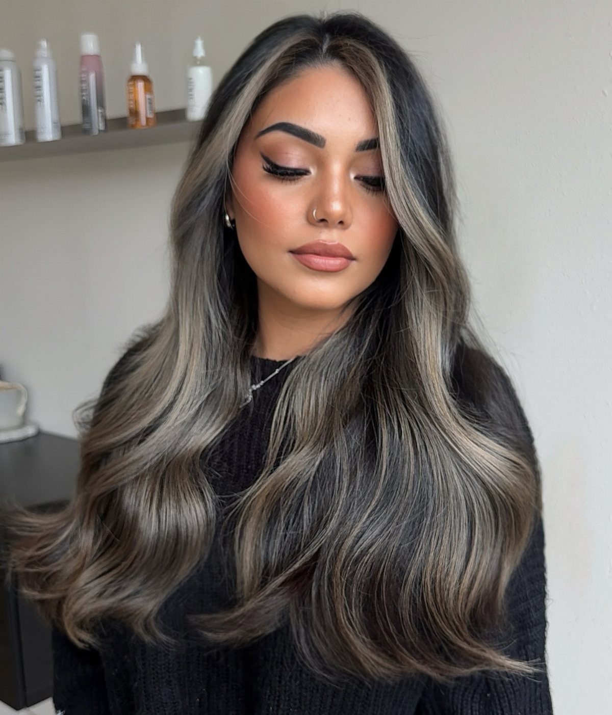 Woman with long dark waves and smoky gray highlights in a salon