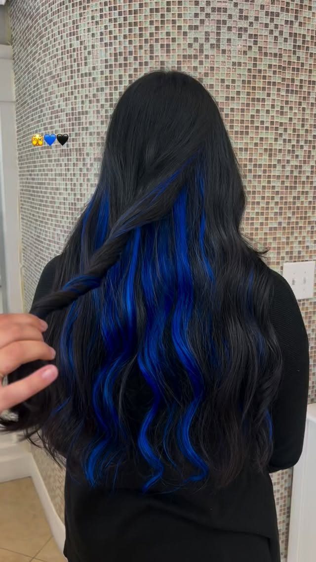 Long black waves reveal vivid electric-blue peekaboo highlights beneath the outer layers