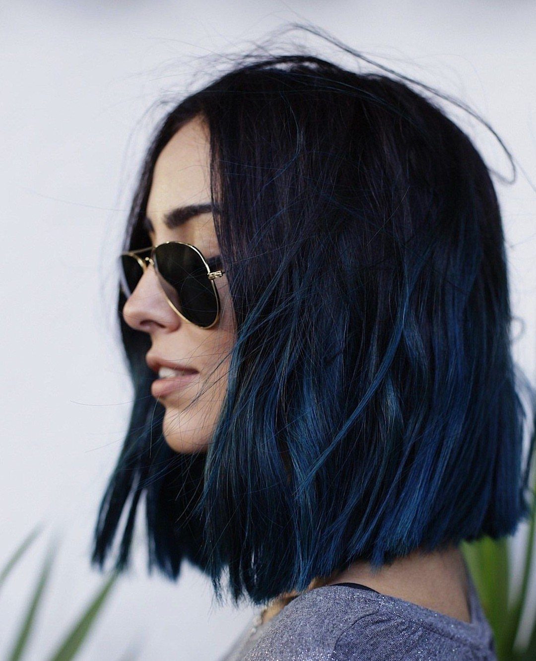 Textured black bob with midnight-blue streaks worn by a person in sunglasses