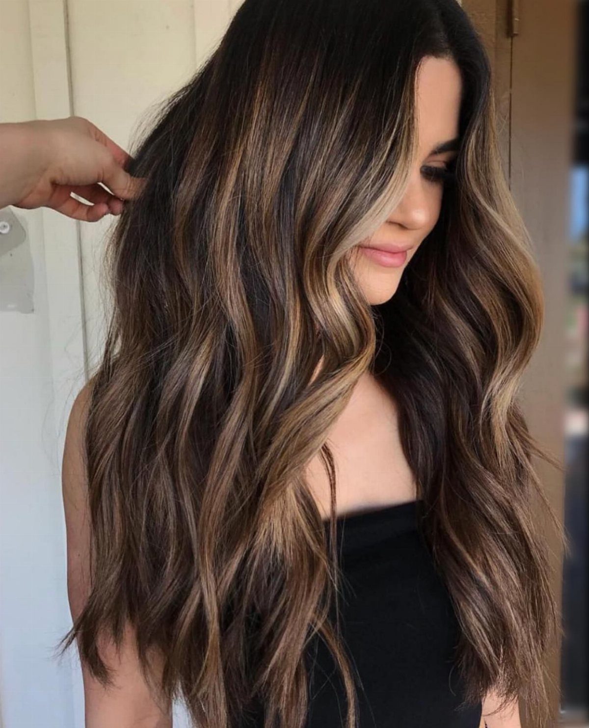 Long glossy dark hair with fine sandy-brown highlights frames a woman's face.