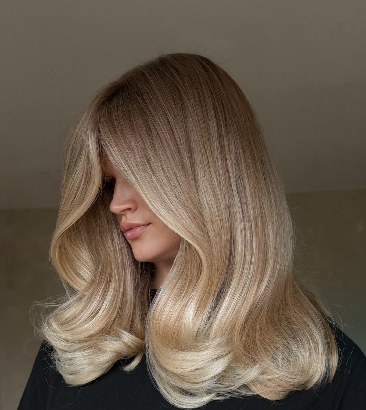 Long blonde hair with bright face-framing highlights and voluminous curled ends