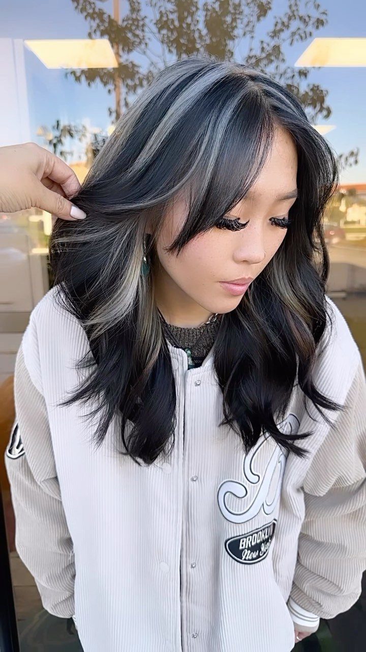Long dark waves with chunky platinum highlights framing the face