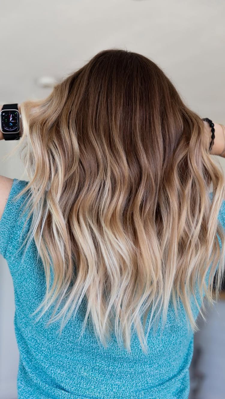 Long wavy hair blends dark roots into creamy beige-blonde ends