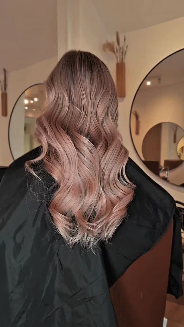Wavy rose-brown hair blends into peachy rose-gold balayage ends