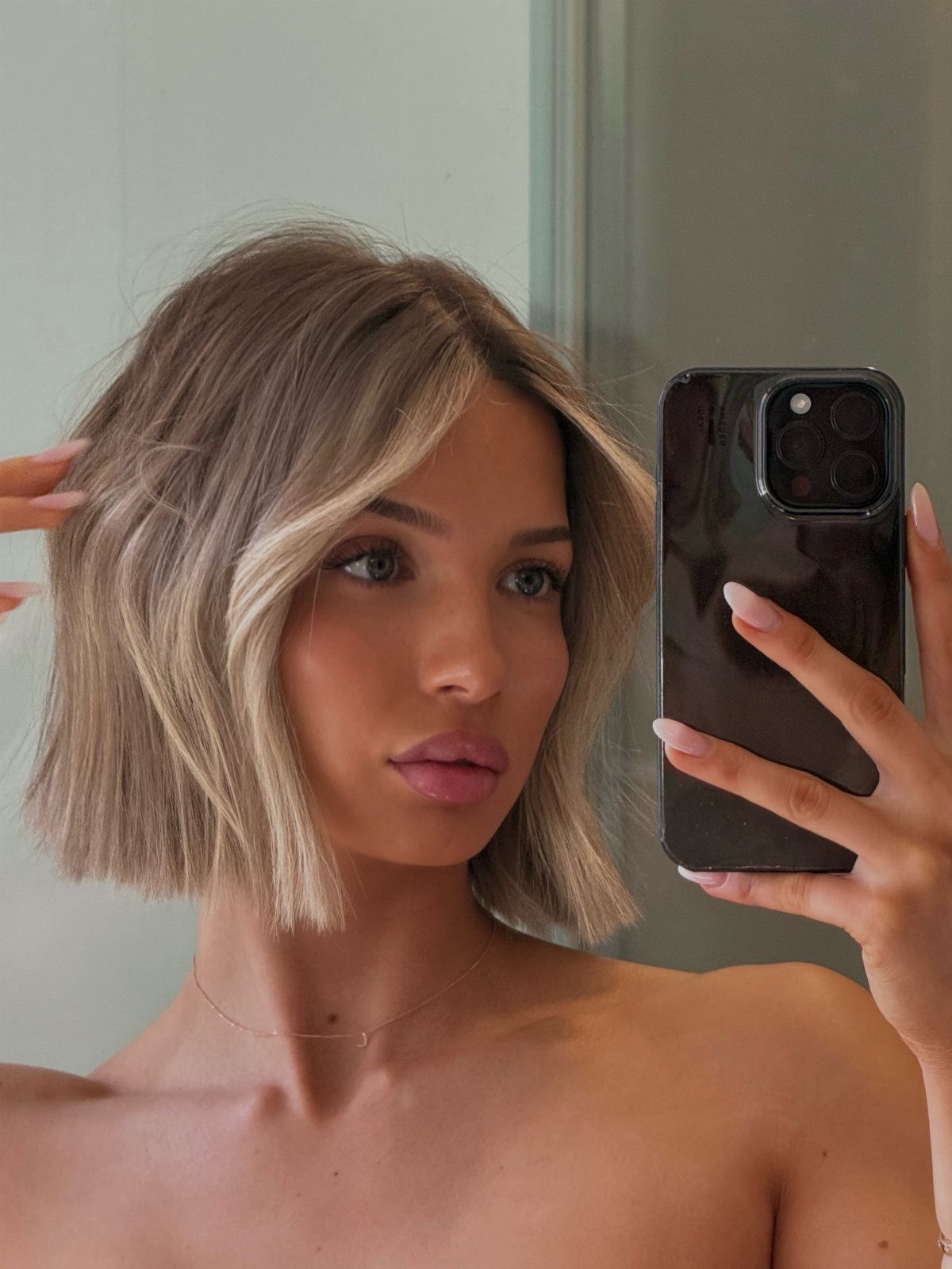 Sleek blonde bob with darker roots and lighter face-framing balayage strands