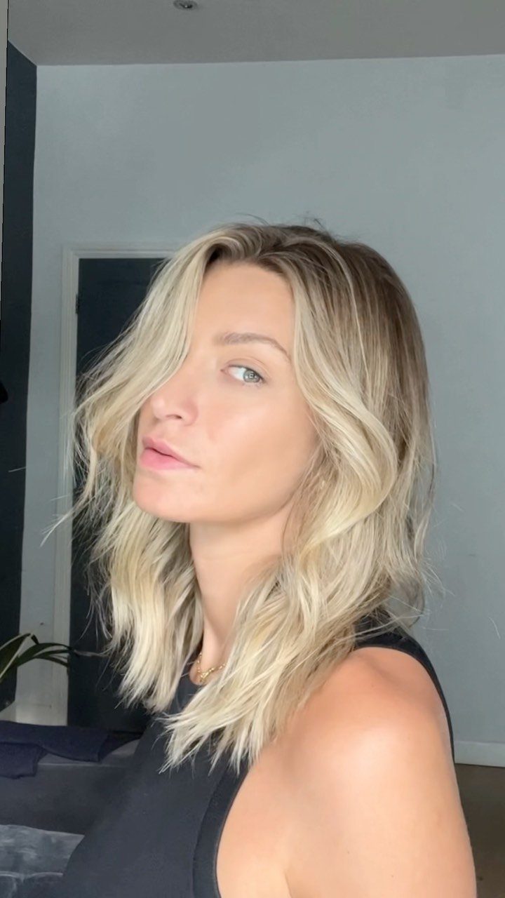 Woman with dark-rooted blonde hair and creamy highlights framing her face