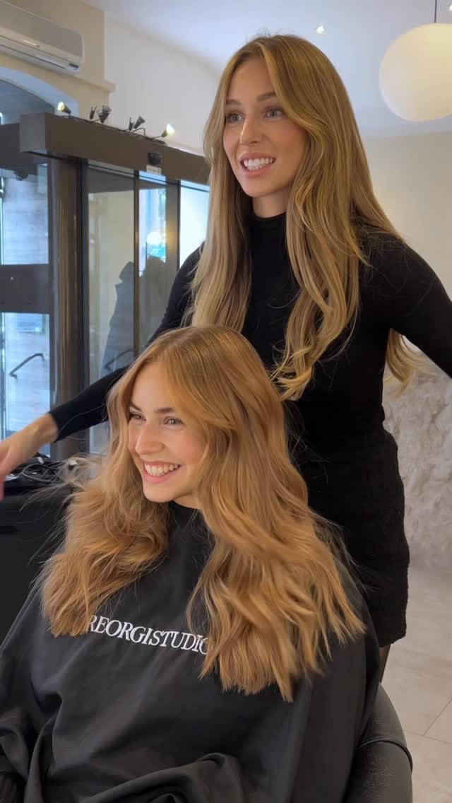 Seated woman shows long, wavy dark honey blonde hair in a salon