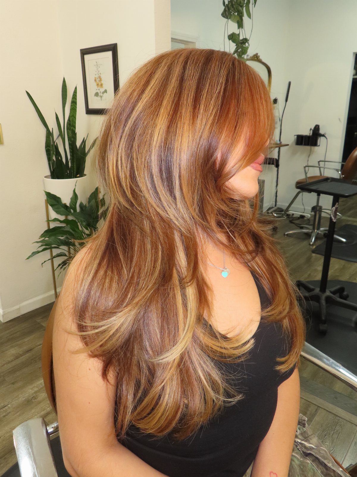 Long layered honey-blonde hair with copper undertones shown in a salon