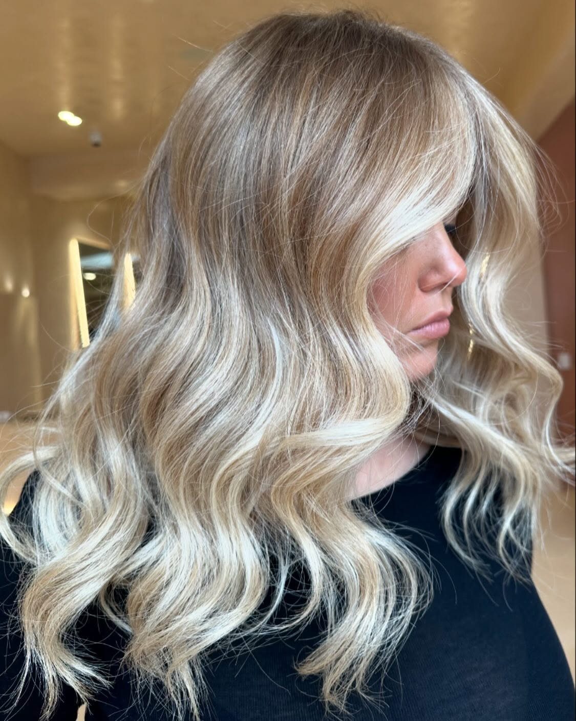 Long wavy blonde hair with bright face-framing highlights on a woman in profile