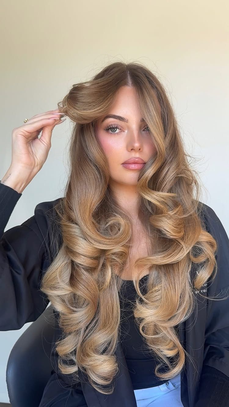 Woman displaying long brown hair with soft honey-blonde ombre balayage waves
