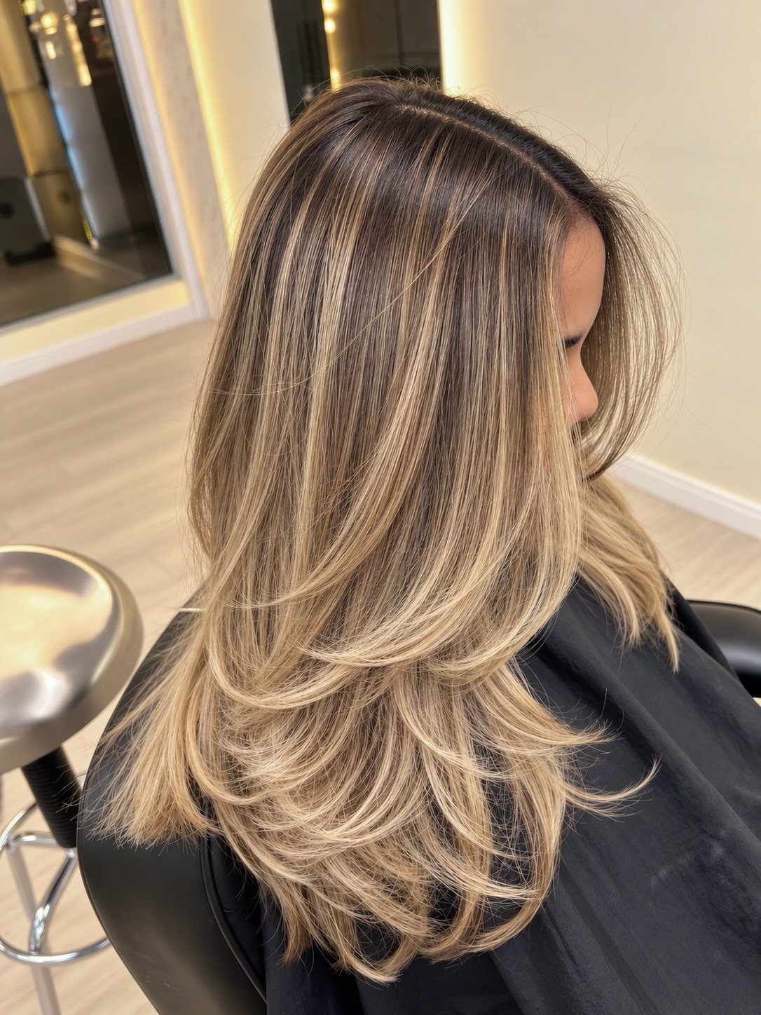 Layered blonde hair with dark roots and sun-kissed honey beige highlights