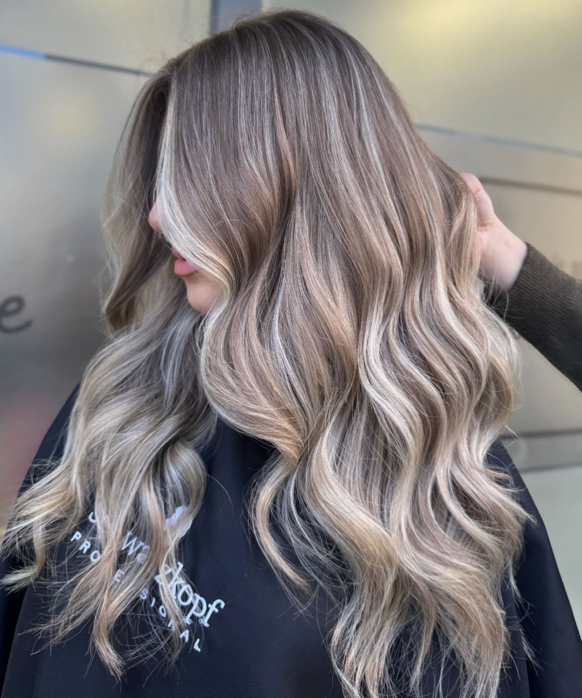 Long wavy blonde hair with cool brown roots and pale highlights