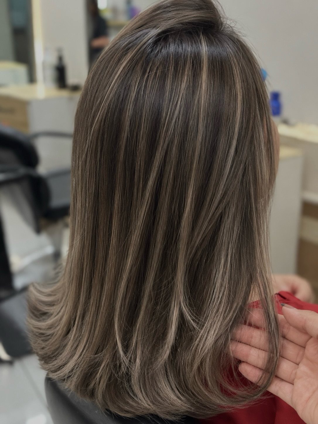 Dark brown hair with cool ash-blonde highlights and softly curled ends
