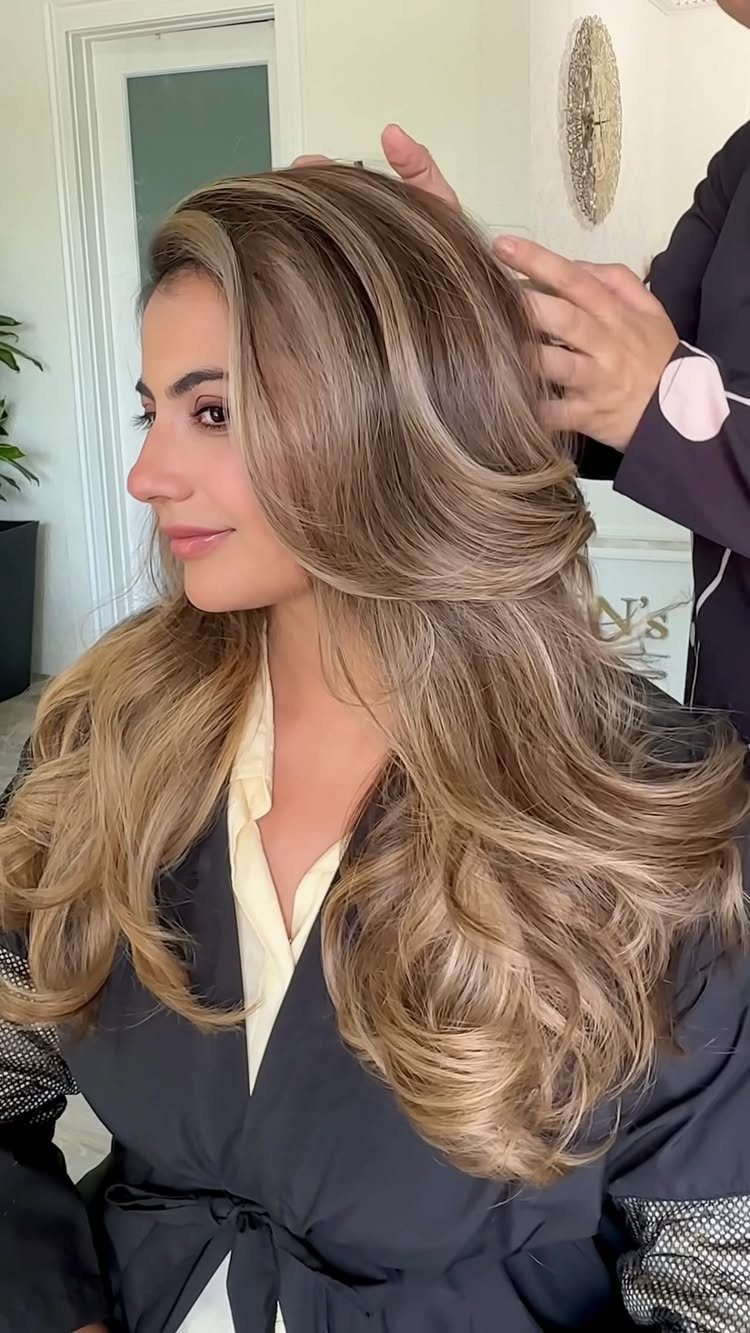Wavy dark brown hair blends into beige blonde highlights in a salon