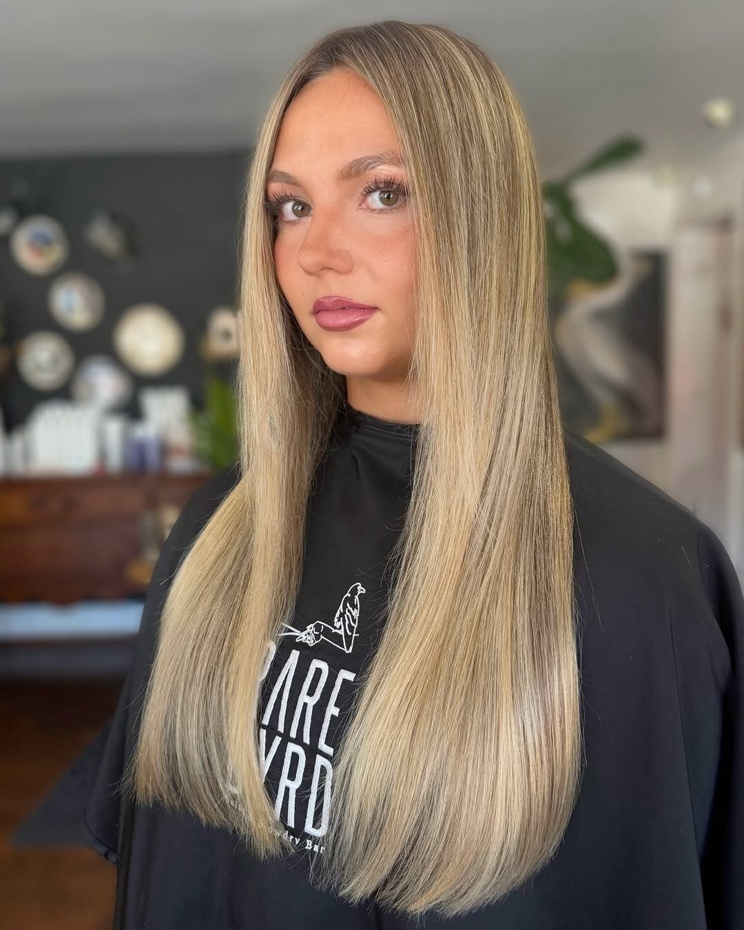 Woman with long straight light brown hair and fine blonde highlights in a salon