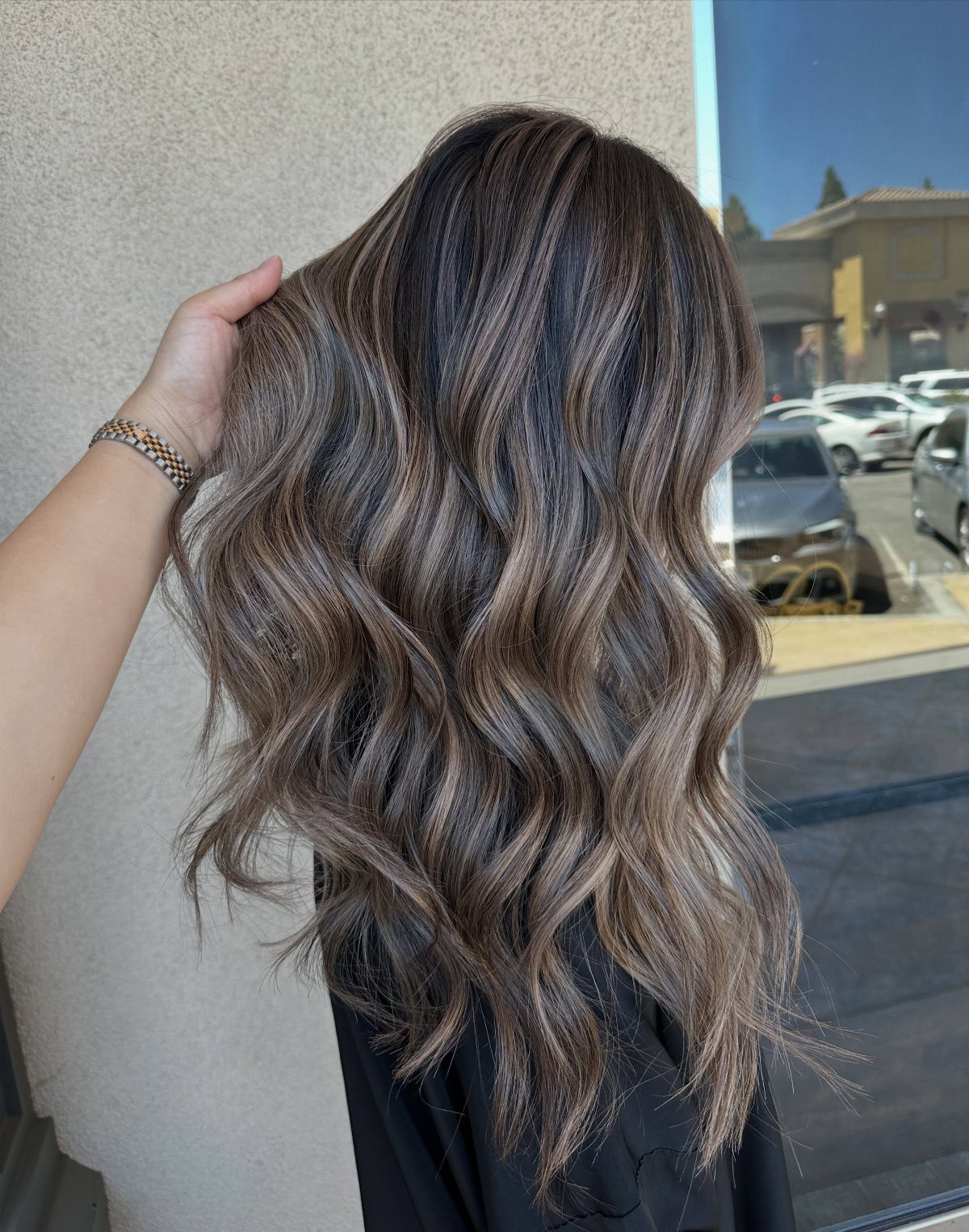 Long dark brown waves show cool ash blonde balayage through the lengths and ends.