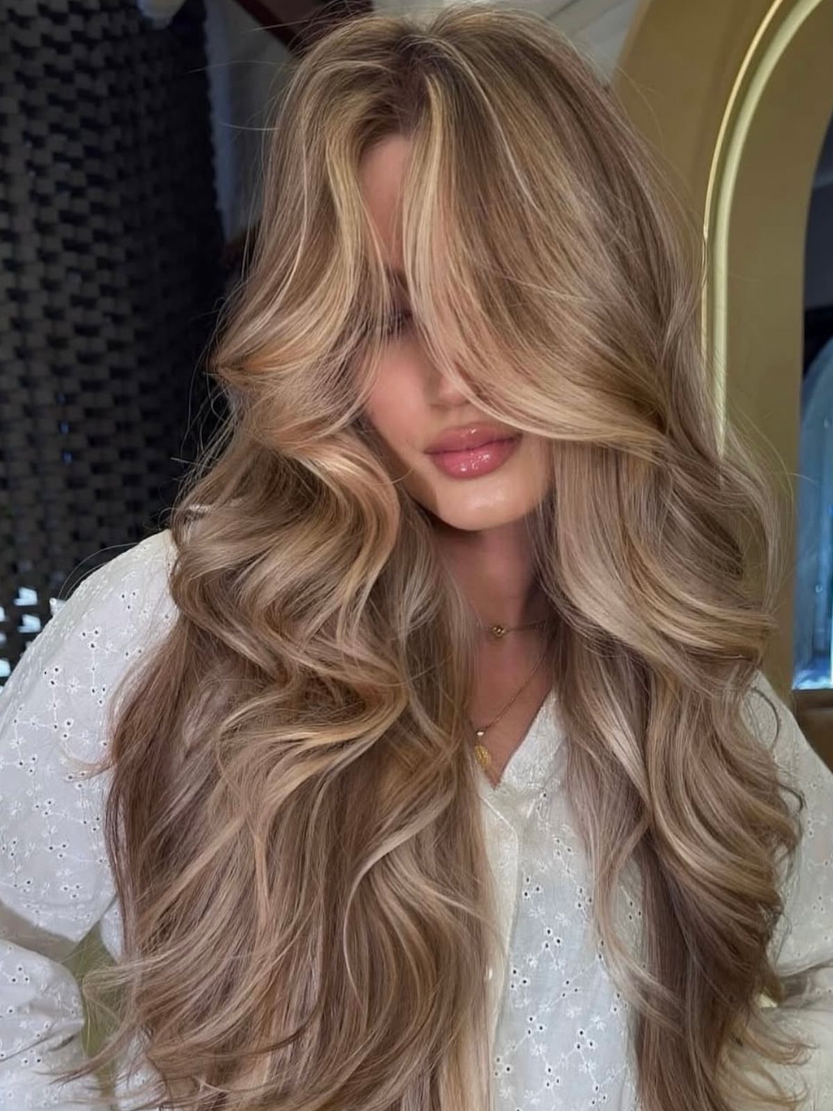 Long wavy blonde hair with dark roots and warm creamy highlights