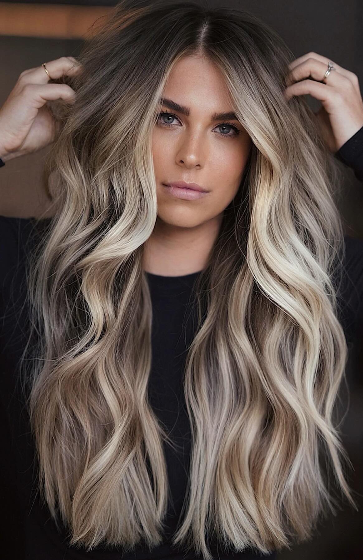 Woman displaying long wavy dark hair with dimensional ash-blonde balayage highlights
