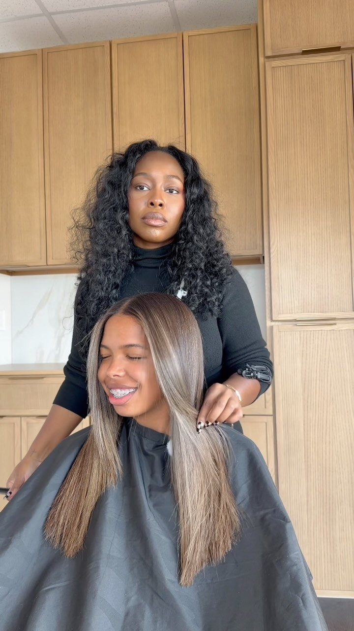 Woman displaying dimensional brown hair with lighter highlights in a salon.