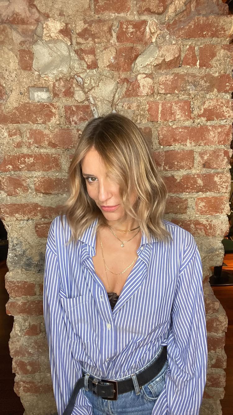 Woman showing shoulder-length blonde hair with darker roots and lighter strands