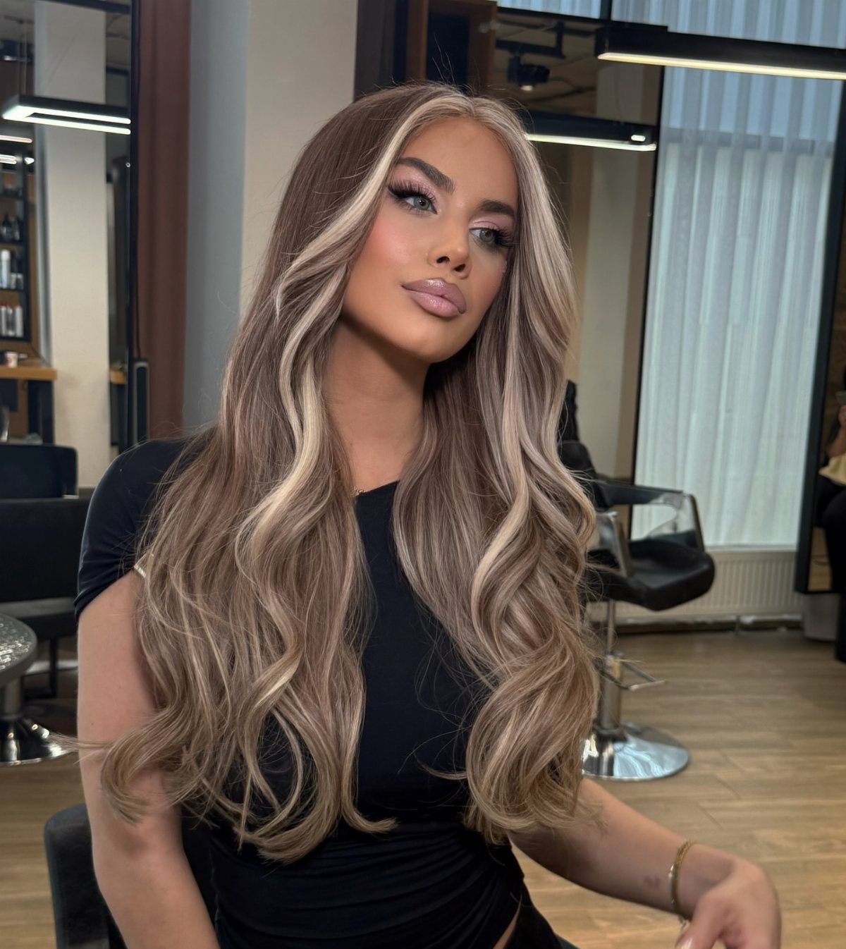 Woman showcasing long dark brown hair with cool ash-blonde highlights and face-framing strands