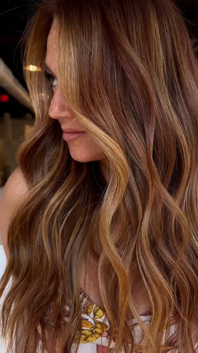 Woman with long brunette waves and golden blonde highlights framing her face