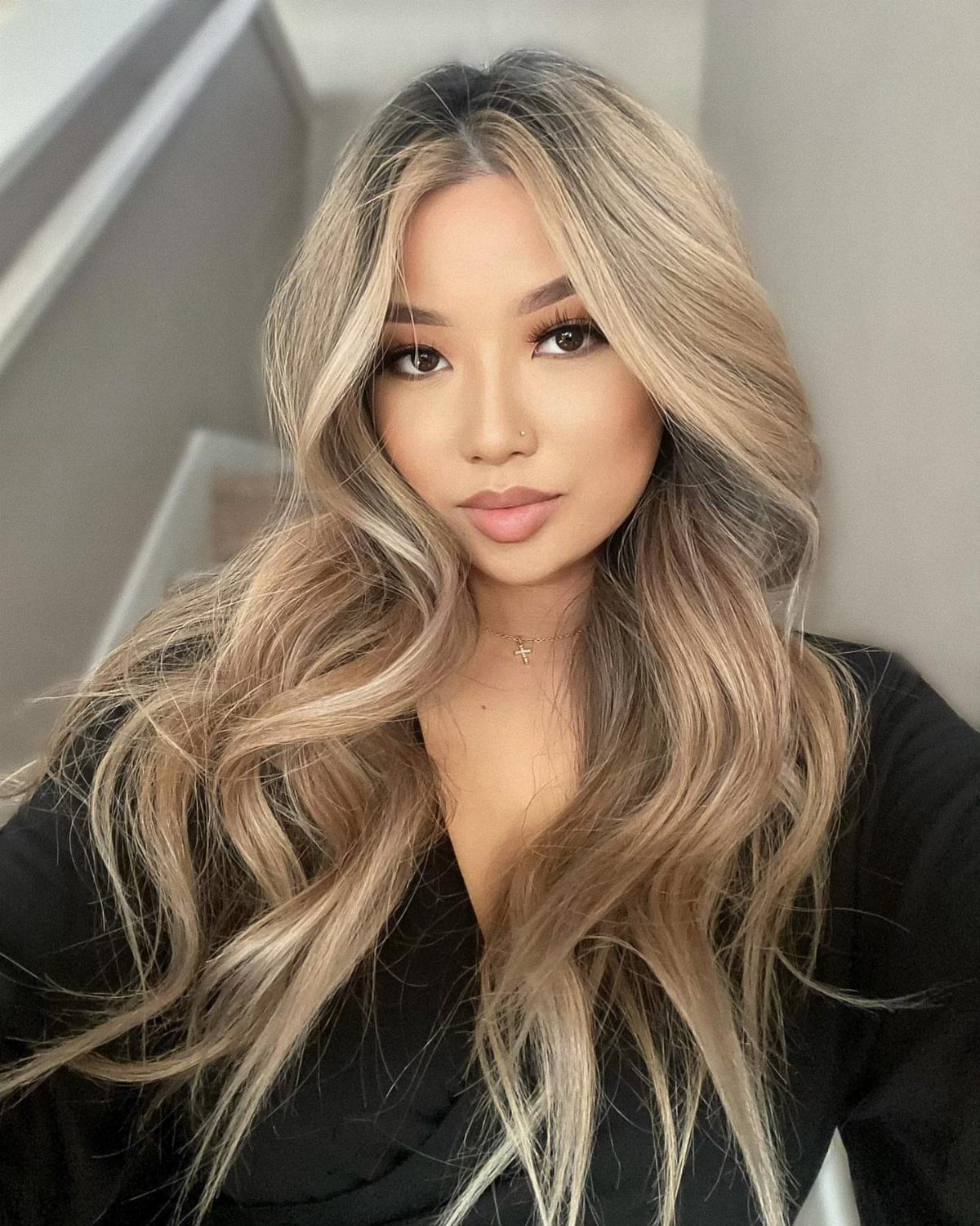 Woman displaying long wavy hair with blended honey, beige, and icy blonde highlights