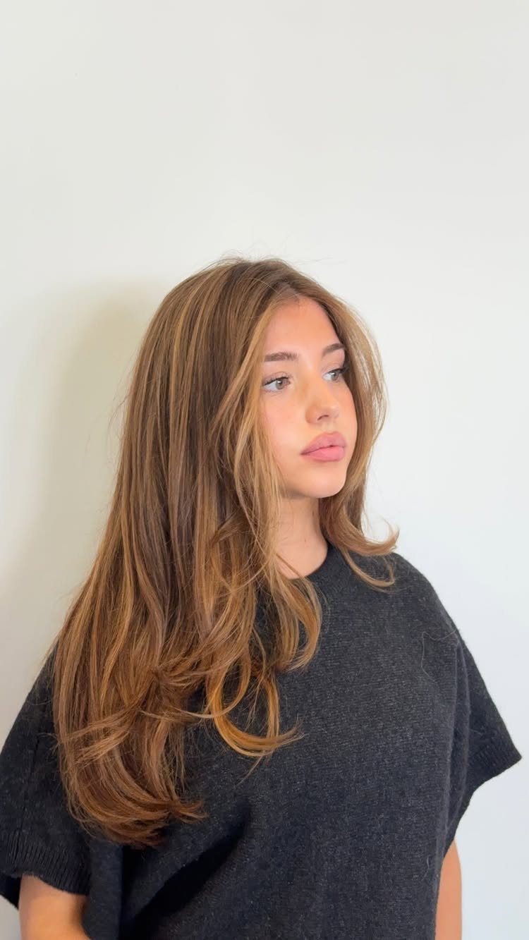 Woman with long brown hair brightened by warm honey-blonde highlights