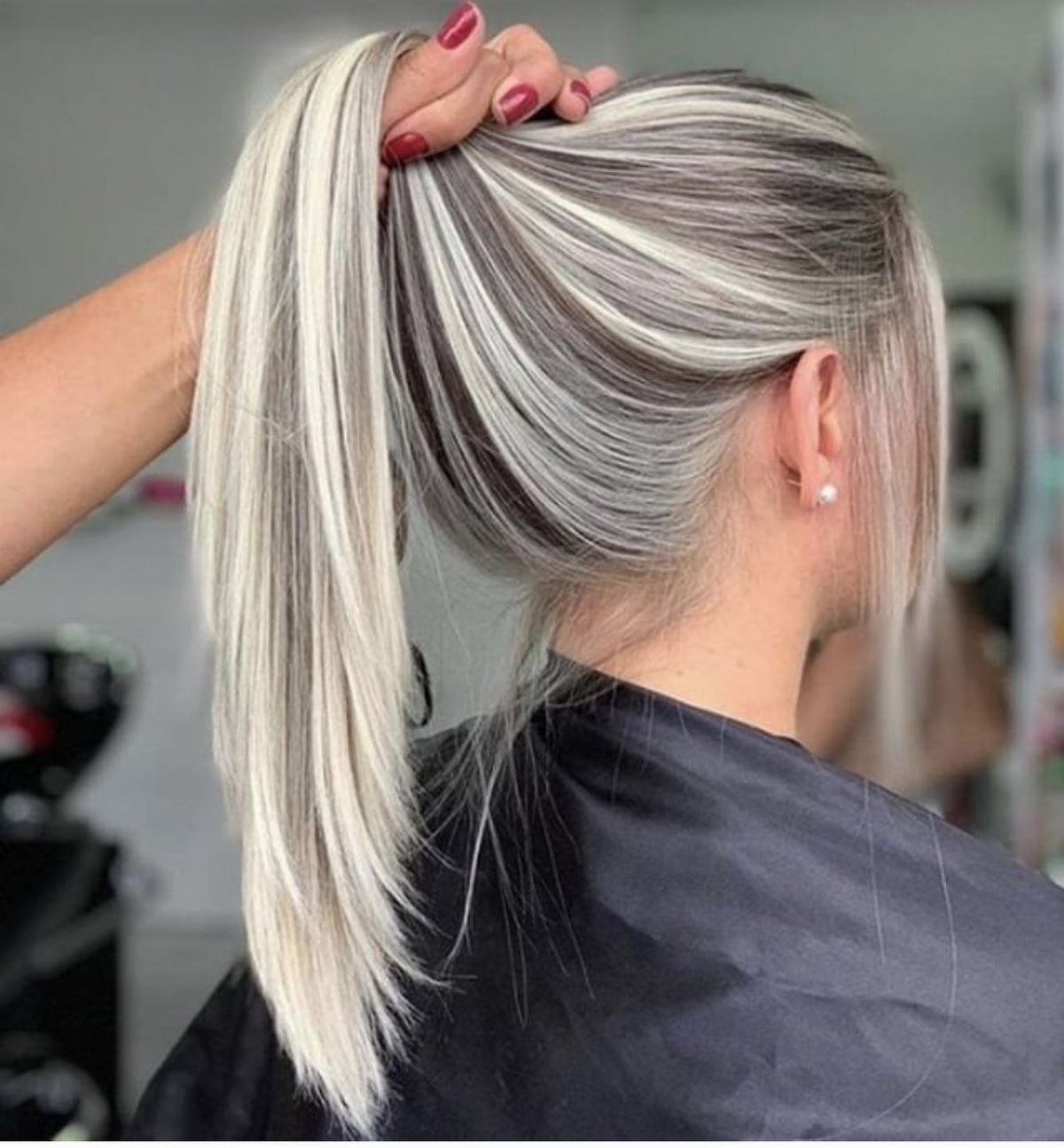 Dark ash-brown hair swept into a ponytail with broad platinum streaks