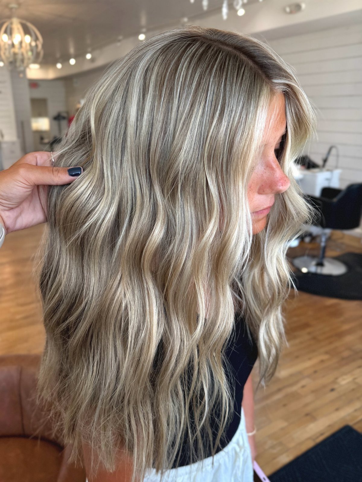 Long wavy blonde hair with dark roots and darker strands through the lengths