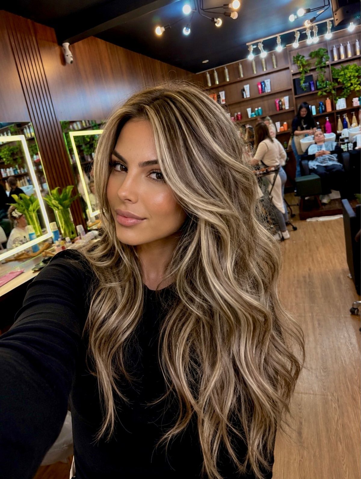 Woman with long, wavy smoky brunette hair and cool blonde highlights in a salon