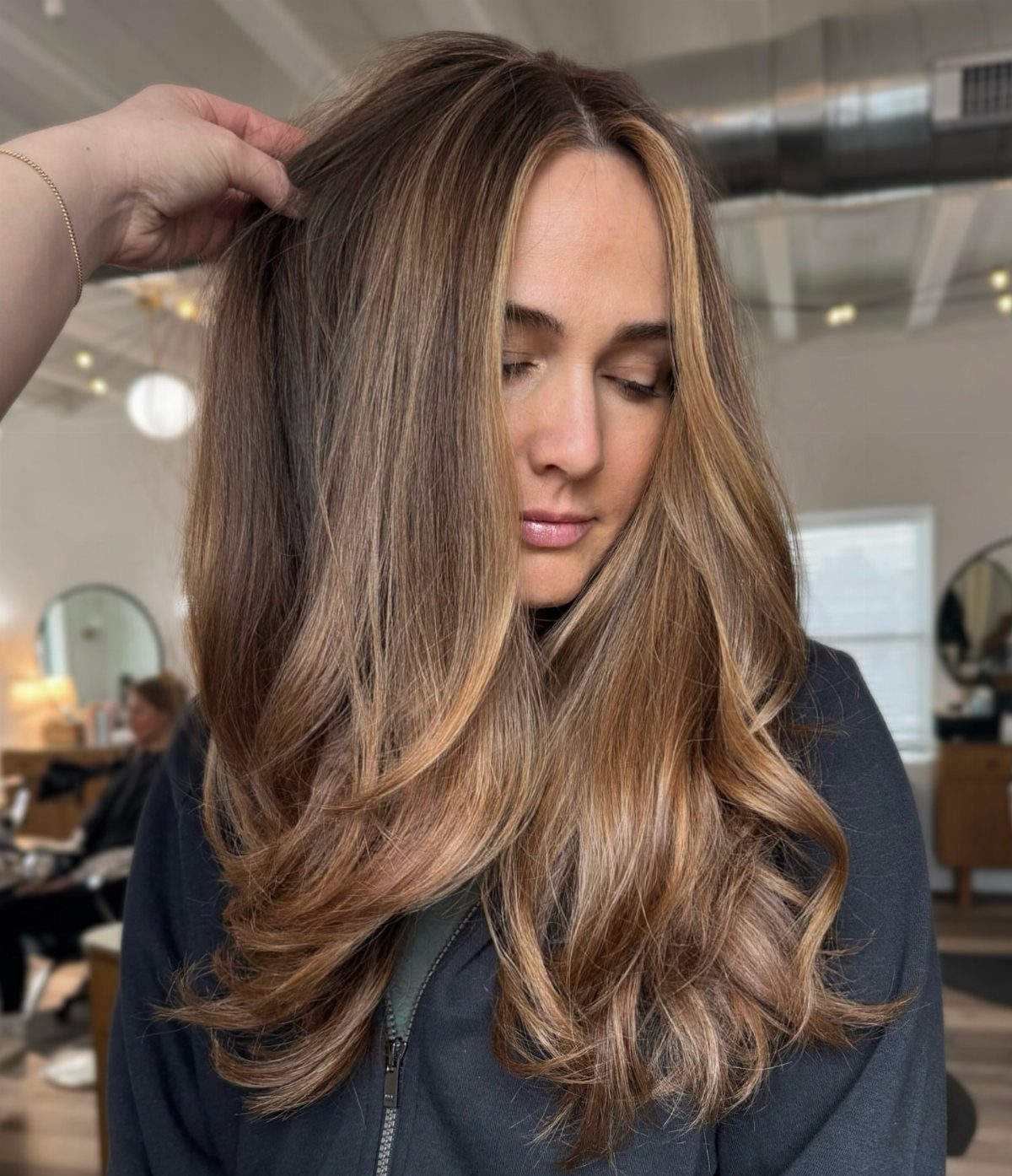 Long layered dark brown hair with blended lighter highlights and curled ends