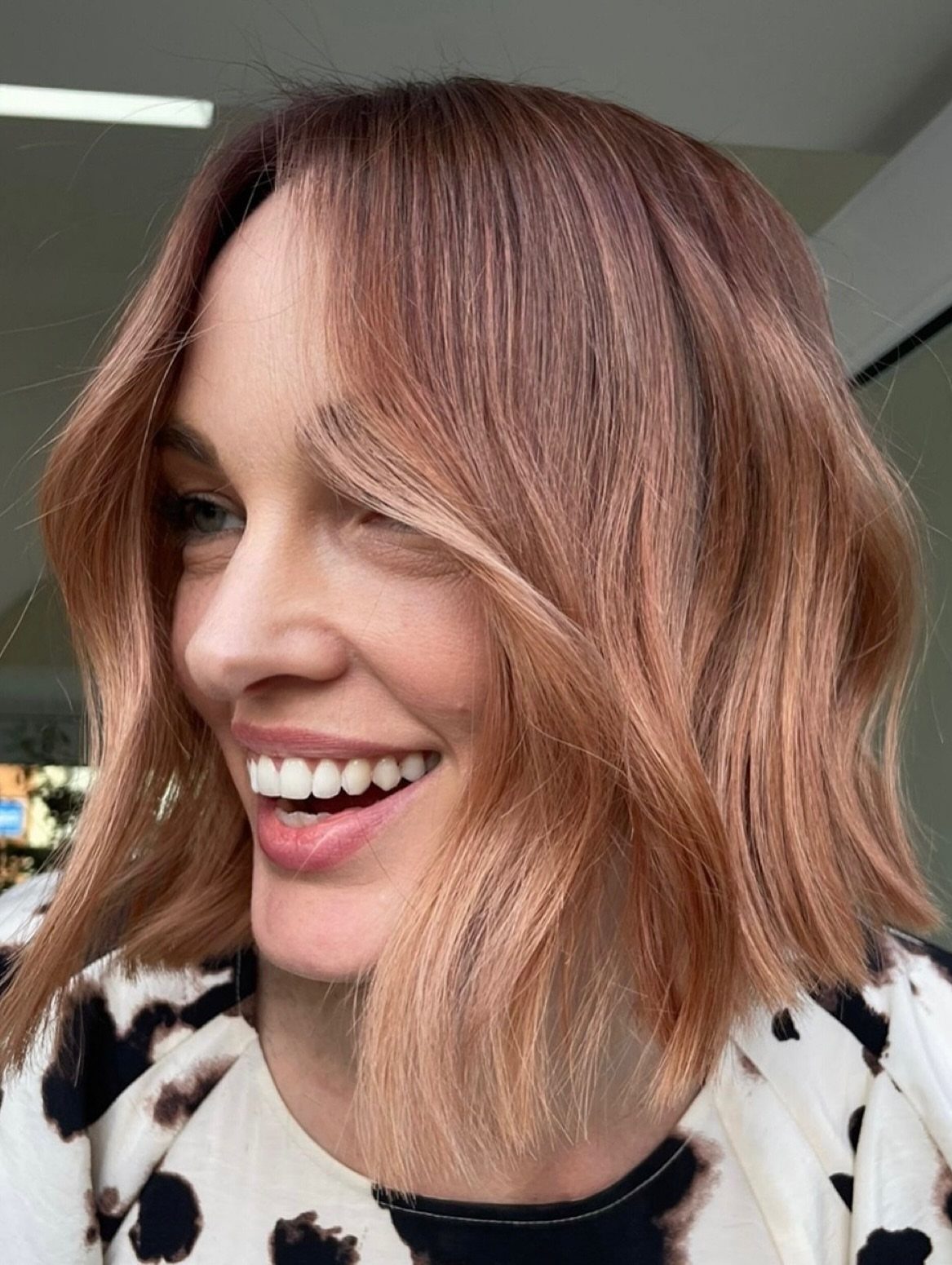 Woman with a copper strawberry-blonde bob and subtle golden highlights