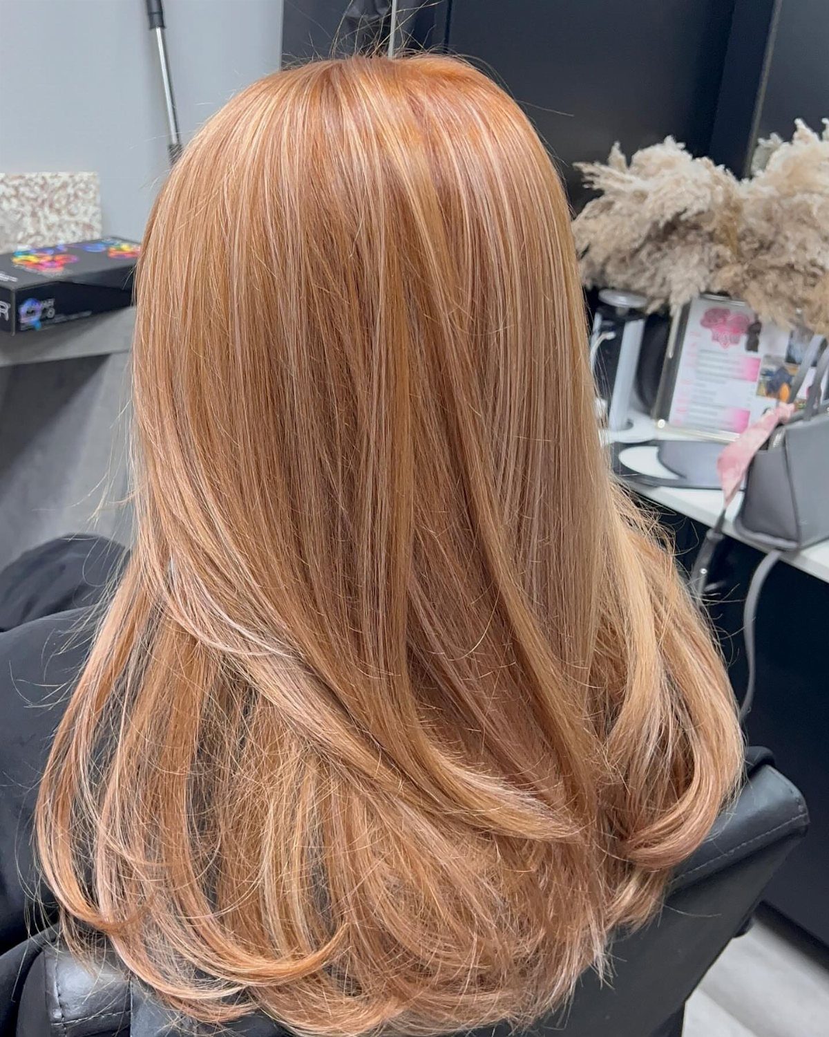 Strawberry blonde hair with copper tones and softly curled ends in a salon