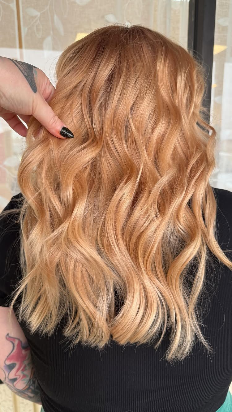 Shoulder-length strawberry blonde lob with loose waves and warm copper tones