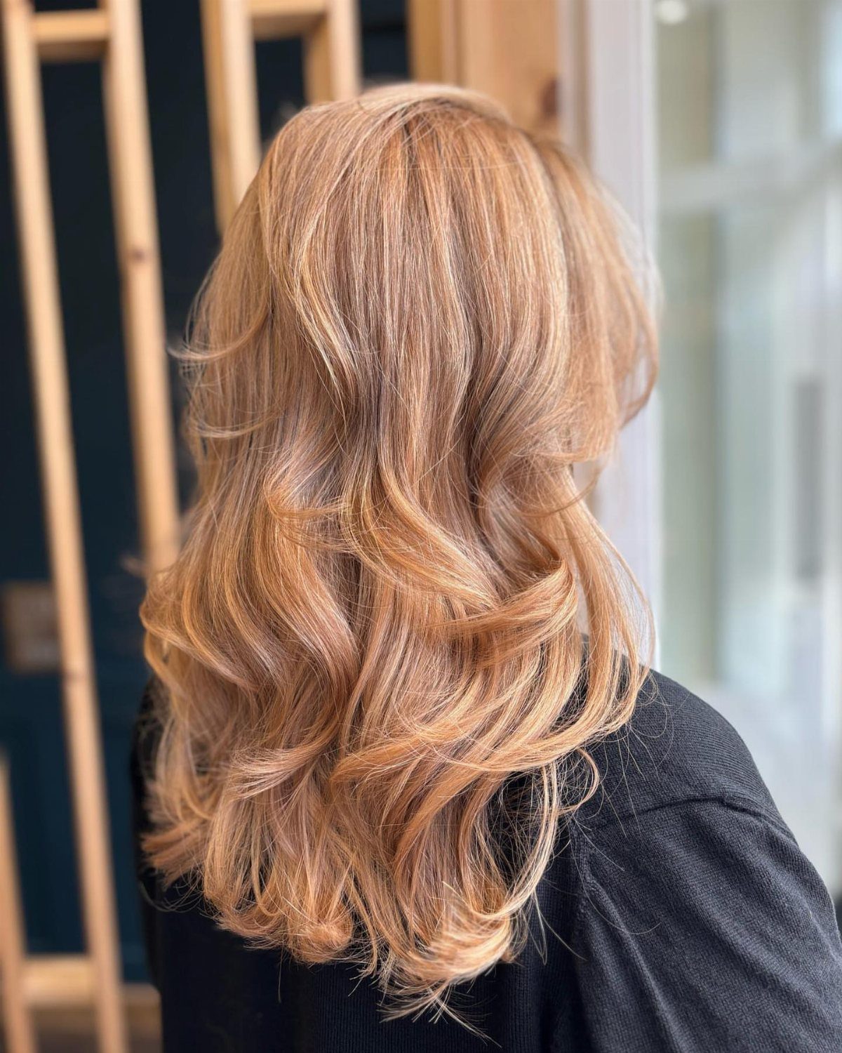 Peachy strawberry-blonde curls with darker roots viewed from behind