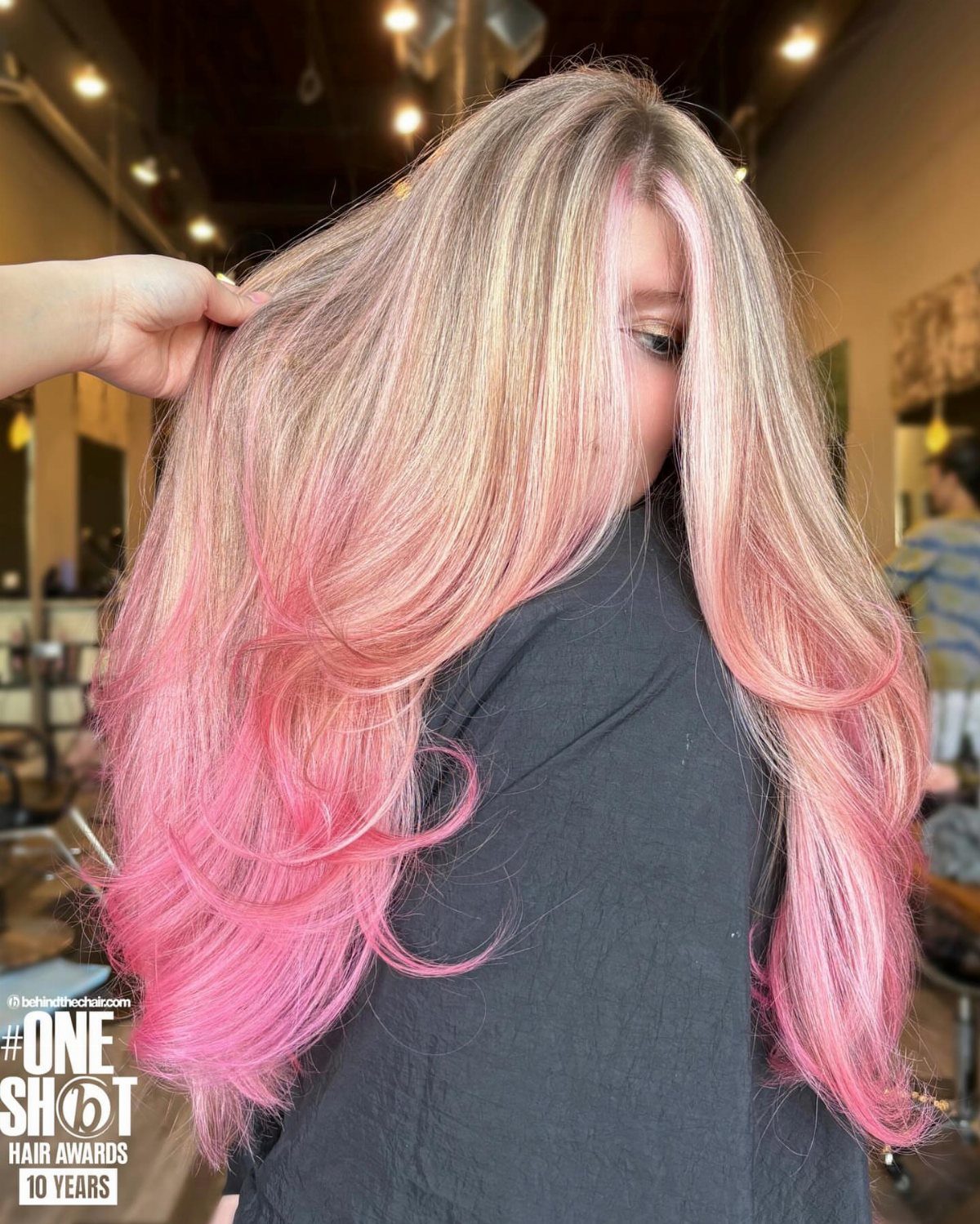 Long blonde hair fades into rosy pink ends in a salon