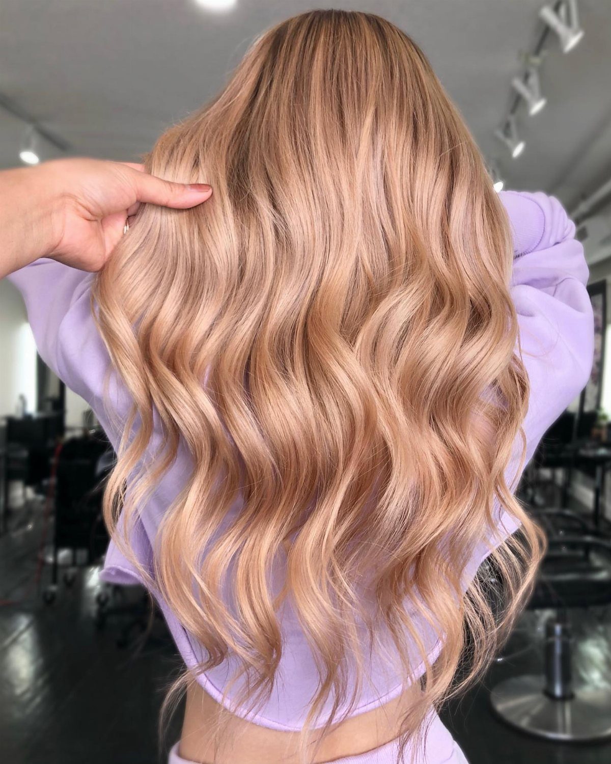 Wavy strawberry-blonde hair with fine, sun-kissed highlights in a salon