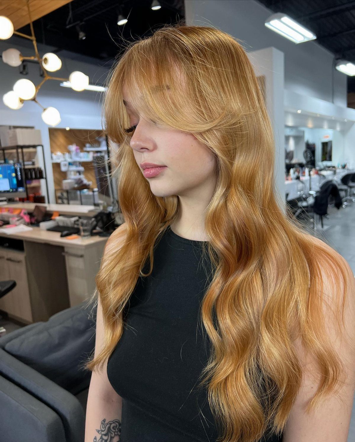 Woman with long strawberry-blonde waves and lighter face-framing pieces in a salon