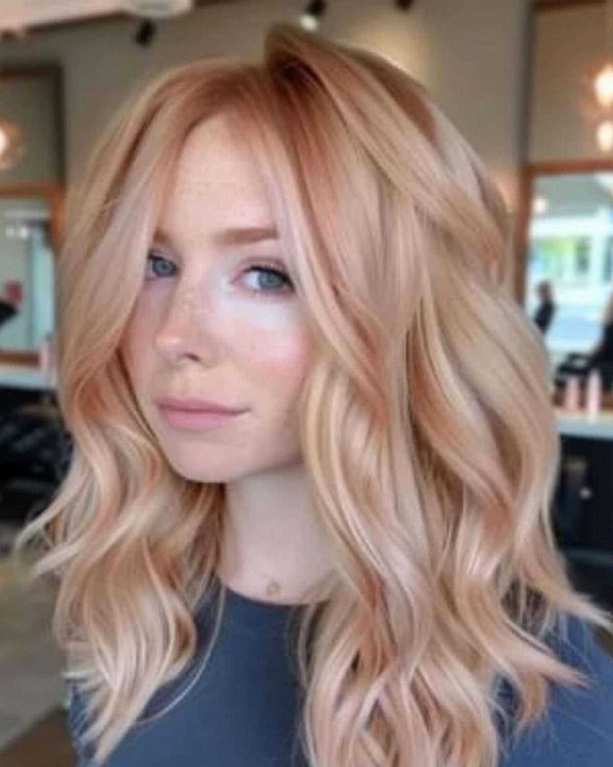 Woman with long wavy strawberry blonde hair and golden brightness through the lengths