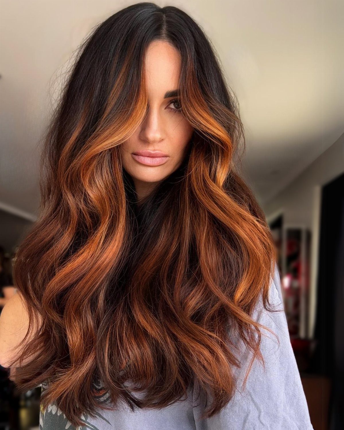 Long auburn waves with copper highlights framing a woman's face