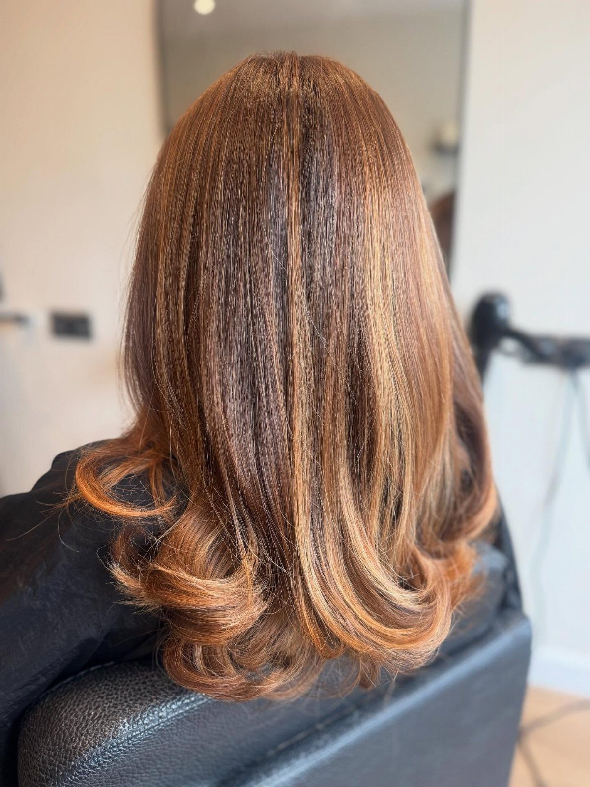 Long auburn hair with copper-orange highlights and softly curled ends